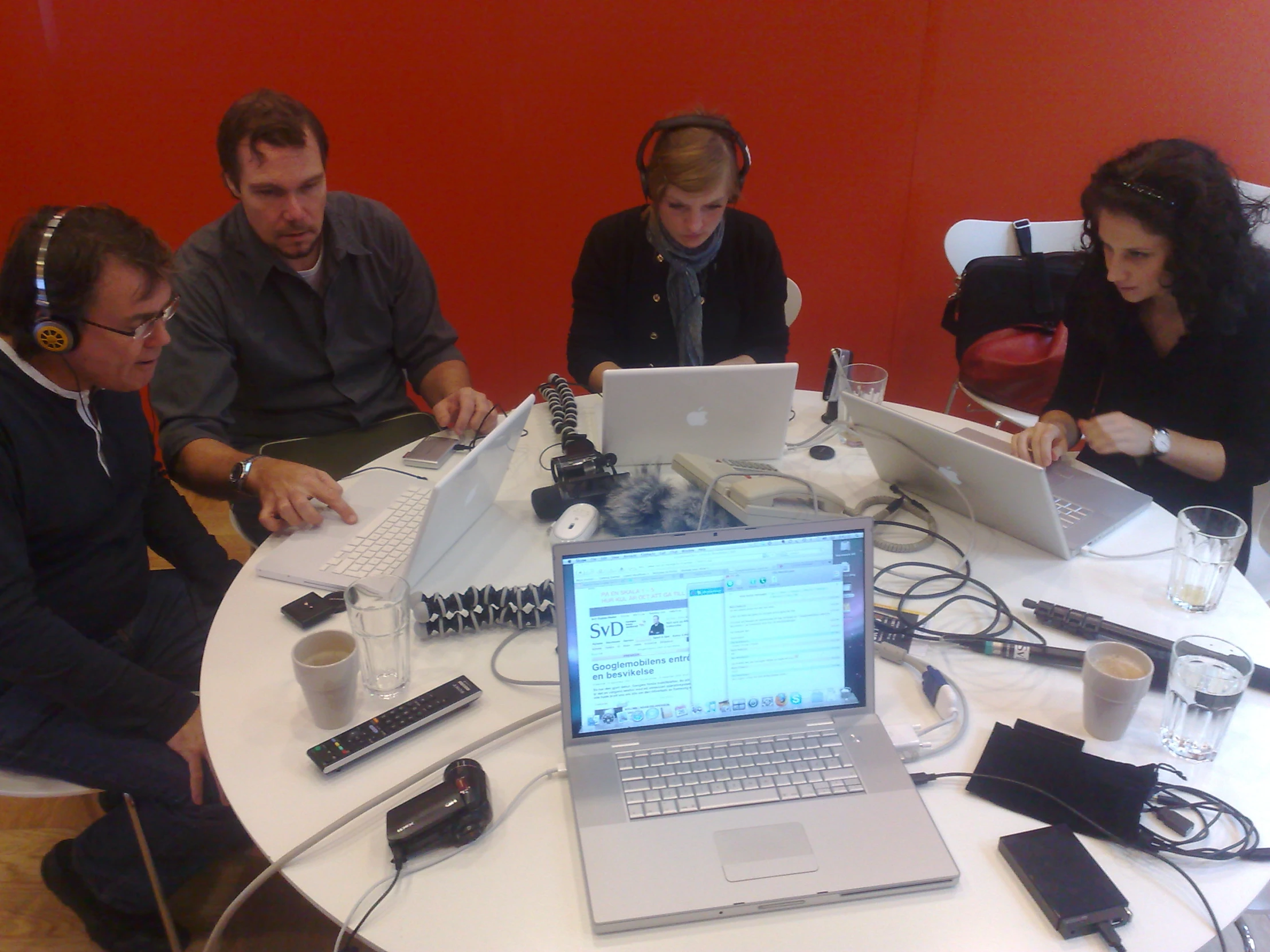 three adults and one is using a laptop on a table