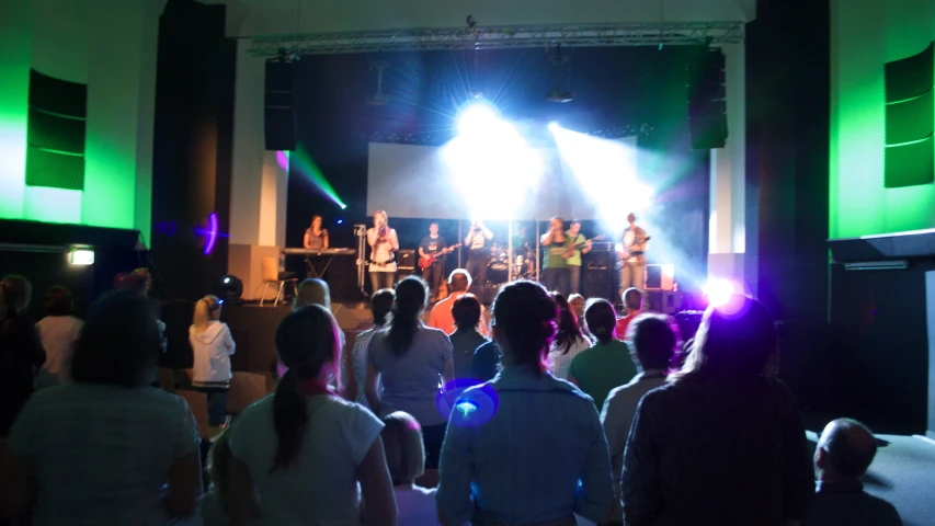 several people sitting in front of a stage while someone on stage gives a speech