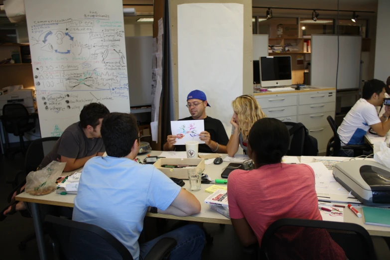 people sitting at a table holding up an object