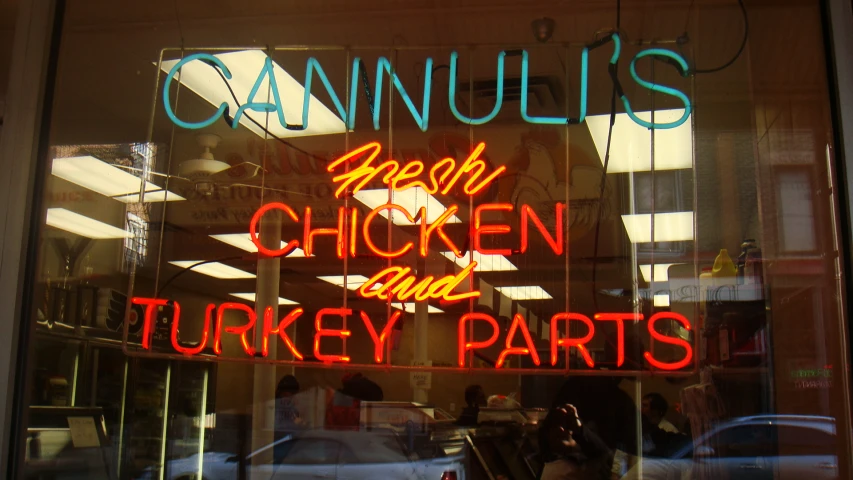 a shop sign in a window saying,'food, chicken and turkey parts '