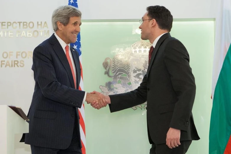 two men shaking hands in front of flags