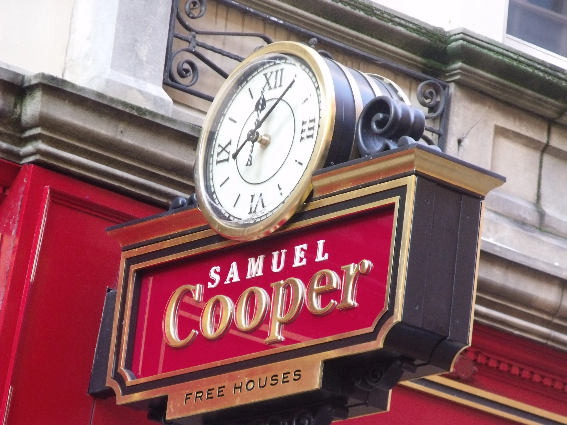 an ornate clock and sign adorn the side of a building