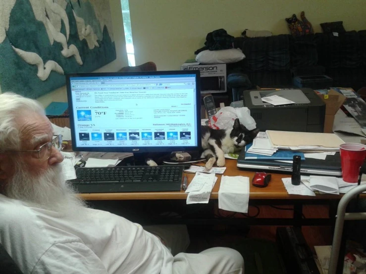 an old man with a beard looking at a computer screen