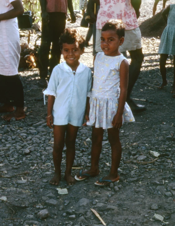 two little boys standing next to each other in the dirt