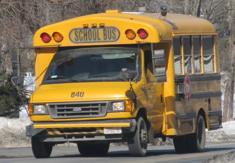 a yellow school bus is parked on the side of a snowy street