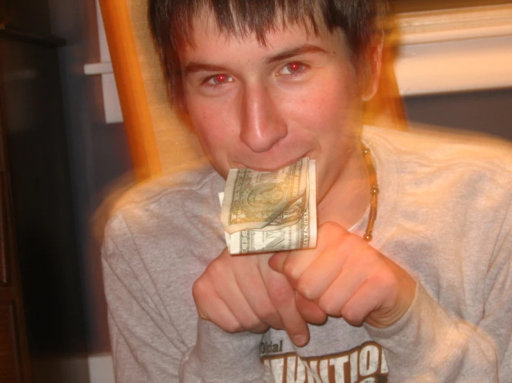 a young man is chewing on money