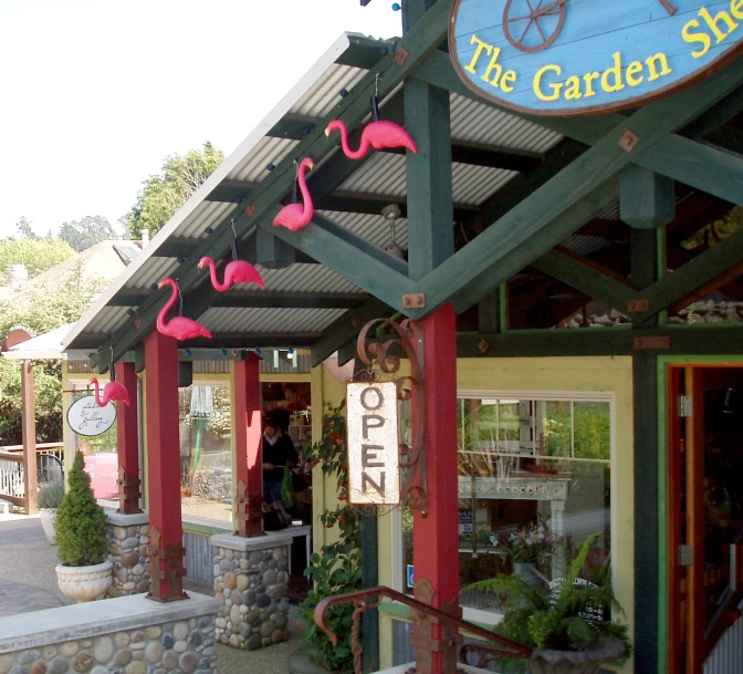 the front of a garden shop with red painted flamingos