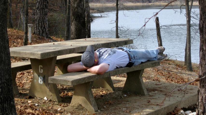 a man in a denim shirt is sleeping on a bench
