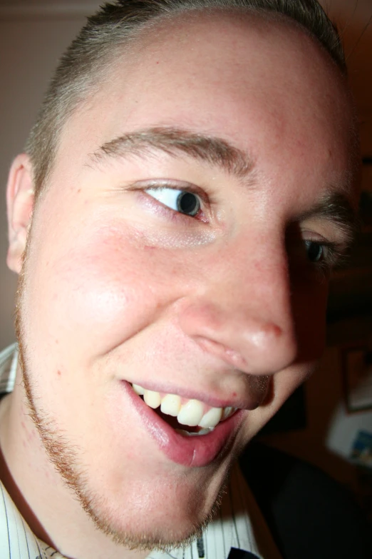 a young man smiling at the camera with his teeth and mouth wide open