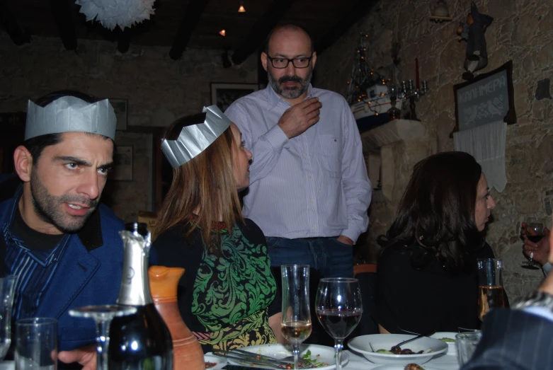 a group of people wearing crowns at a dinner table