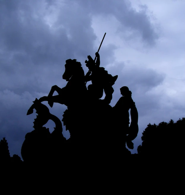 silhouetted statues against dark cloudy sky on an outdoor clock tower