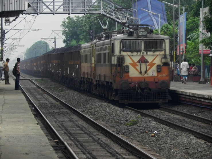 a train pulling into a station with people walking near it