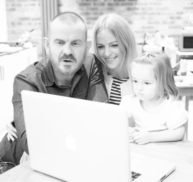 a man and a woman and their young daughter looking at the laptop screen
