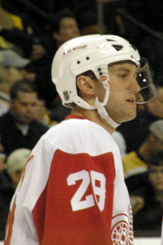 a young man on the ice is wearing a red and white jersey