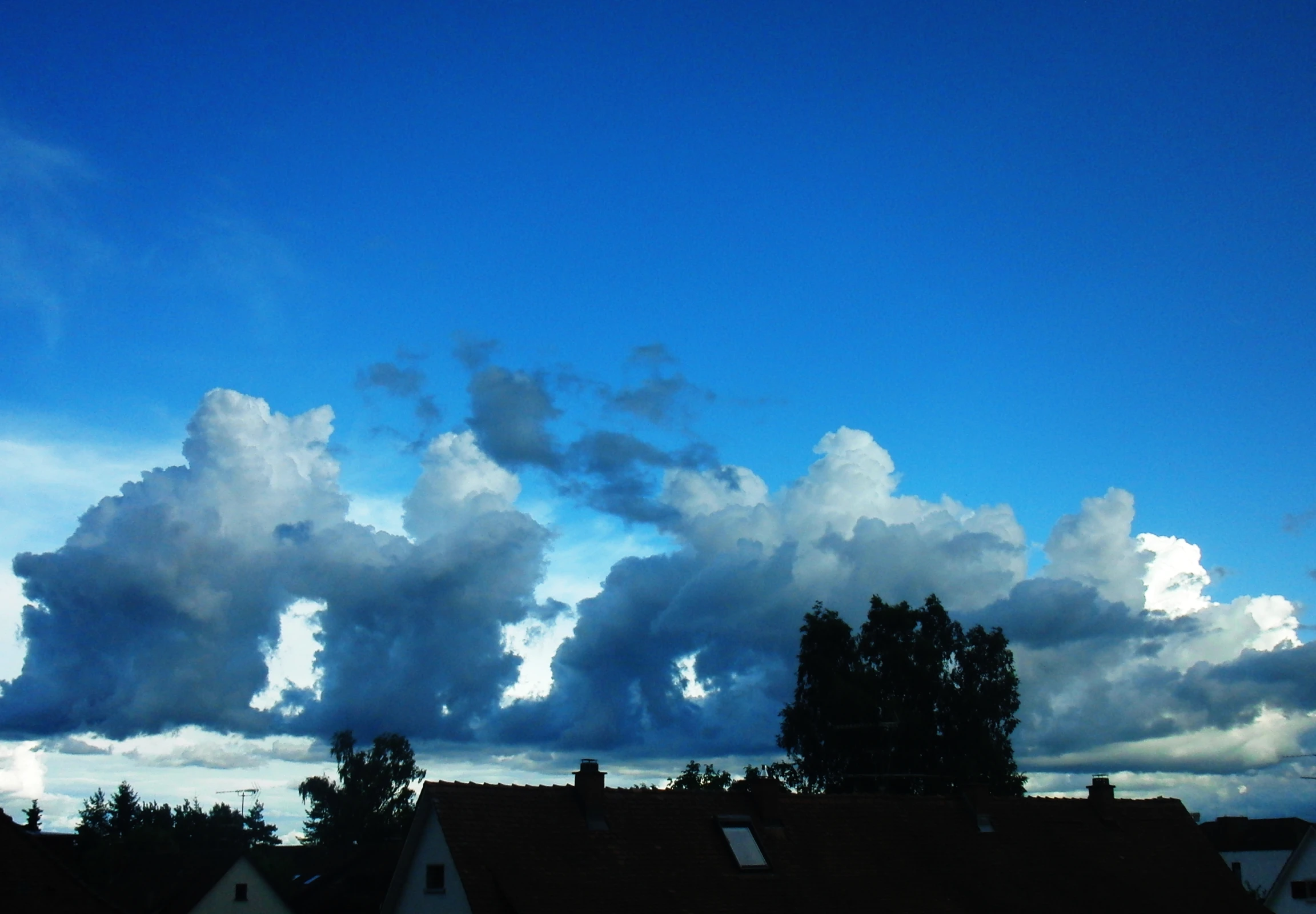 the clouds above houses with buildings in front