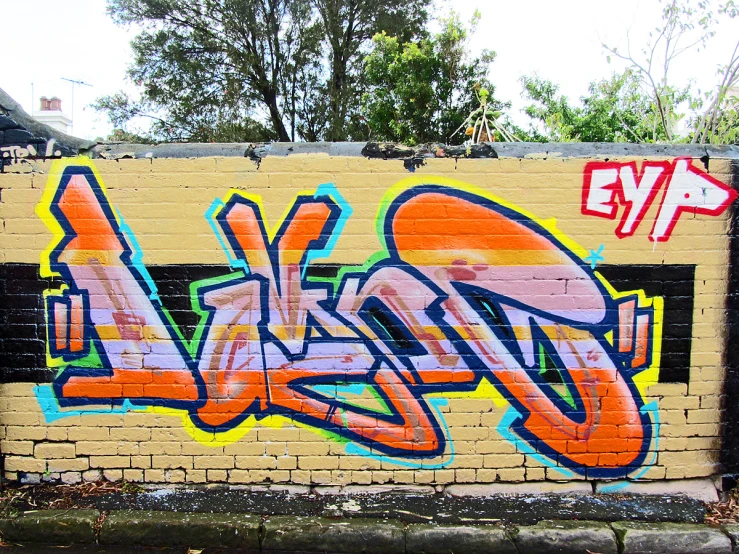 a graffitti wall is next to a tree