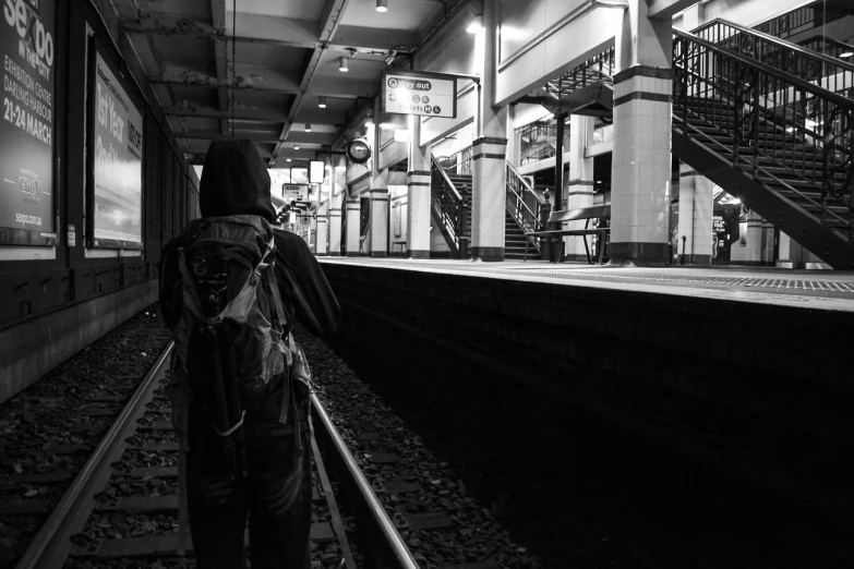 a person wearing a backpack walking along train tracks