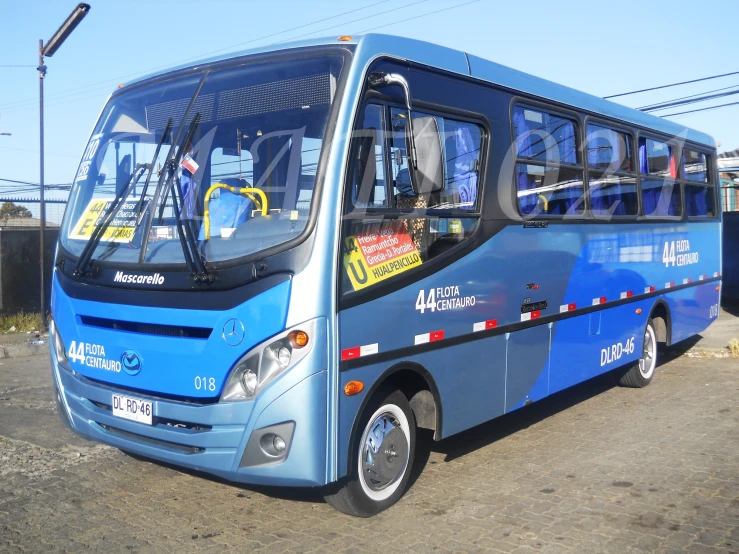 a blue bus sitting in the street with a man looking on