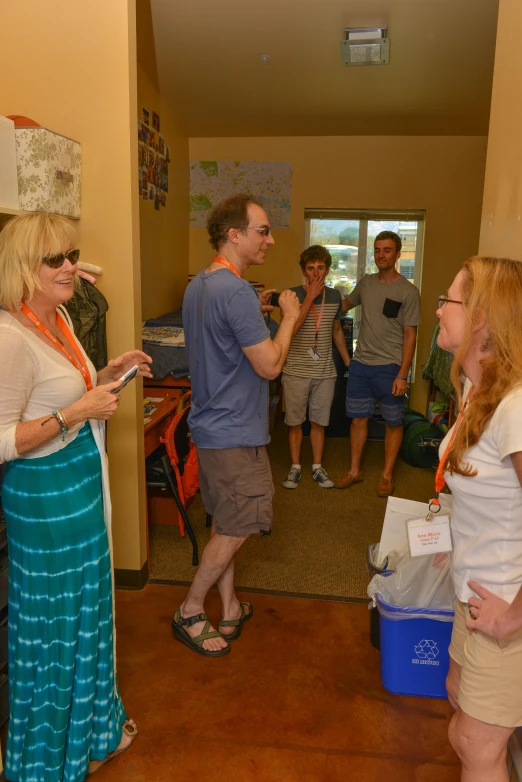 three people talking while walking into a room with other people standing around