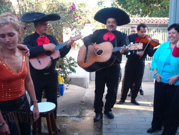 four people are dressed in mexican style outfits and playing guitars