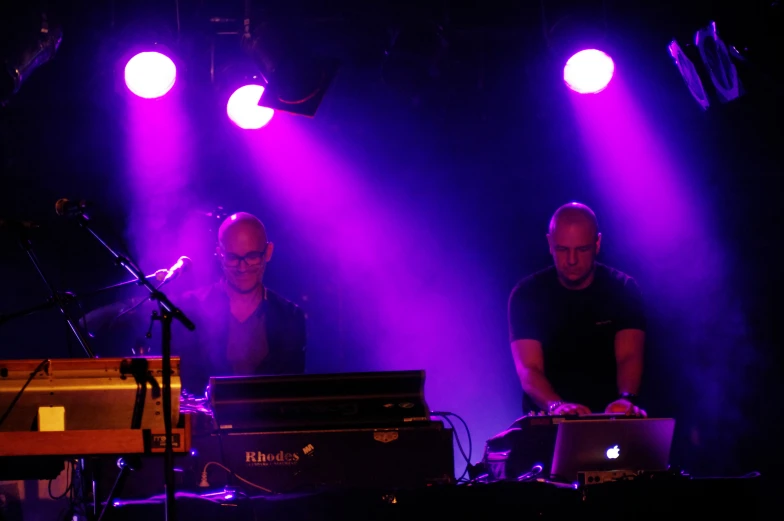 two men in the spotlight with keyboards and lights on stage