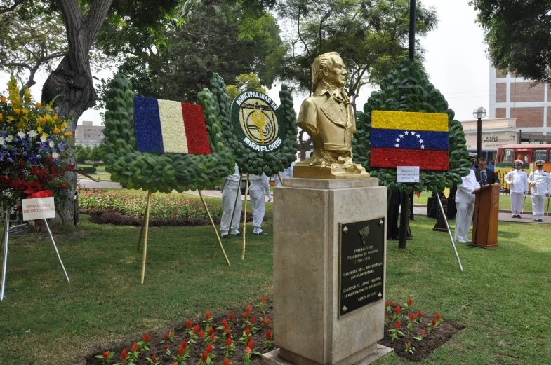 a statue with multiple flags around it in the middle of a field