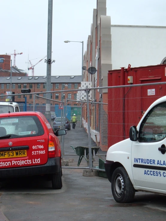 two cars parked side by side next to a fence