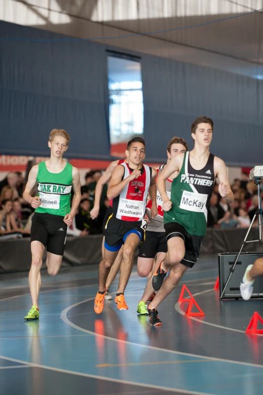 a group of men running on a track with people watching