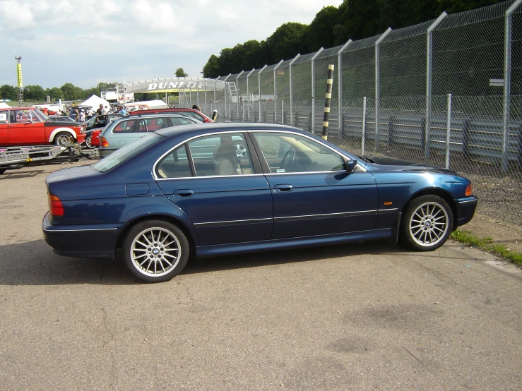 a blue car is parked in front of a fence