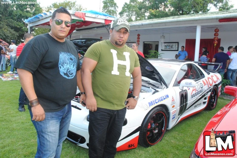 two men stand beside a race car that was modified for charity drive