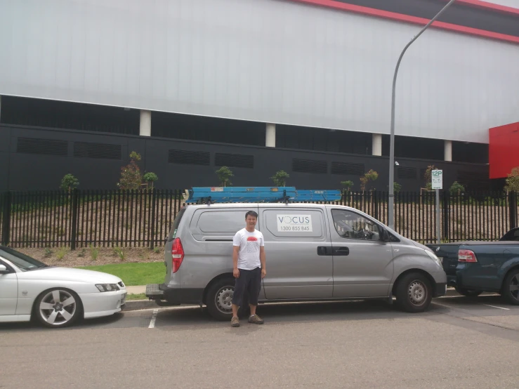 the man is standing in front of a silver van