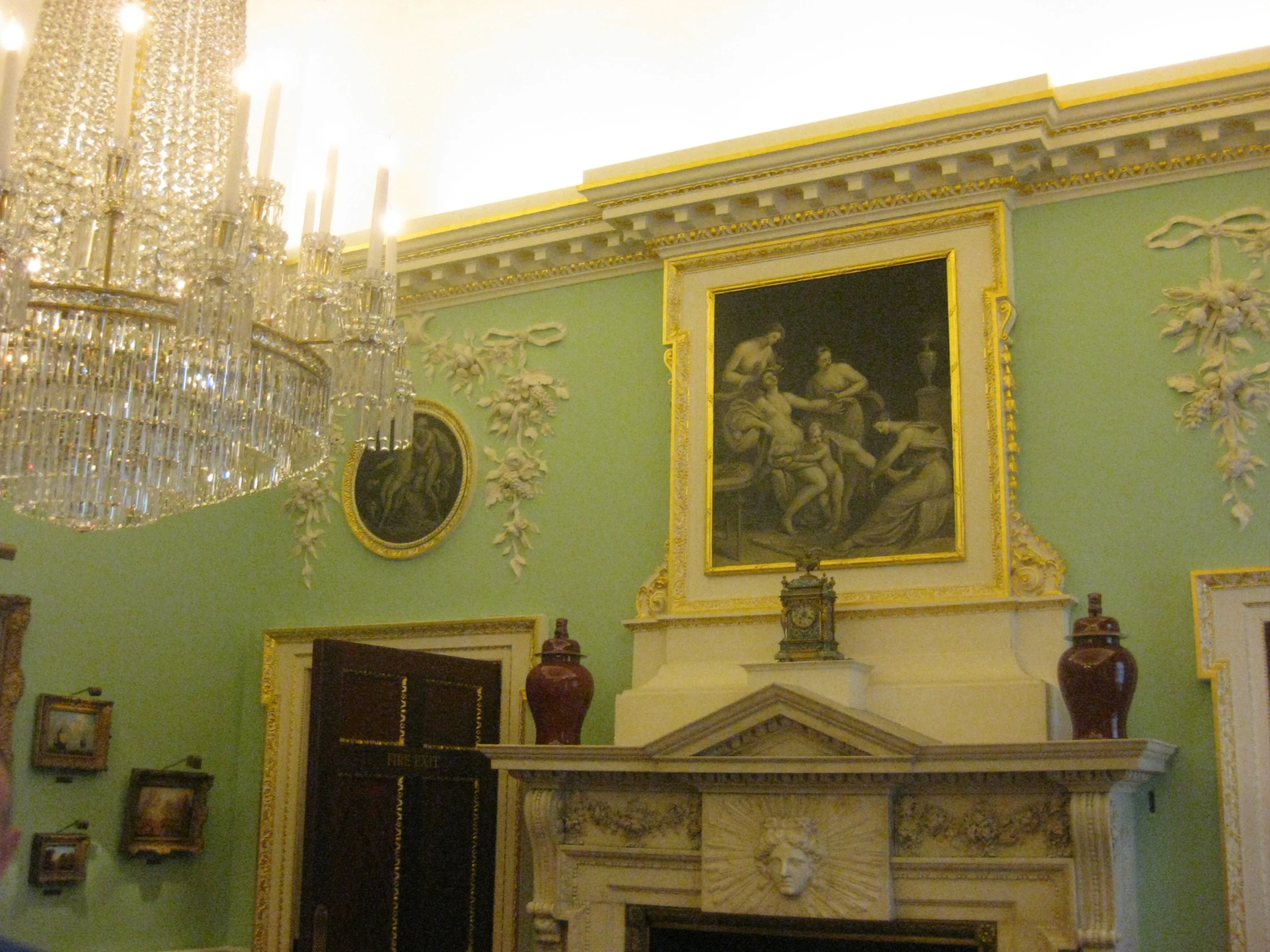 a room with a fireplace and chandelier and paintings