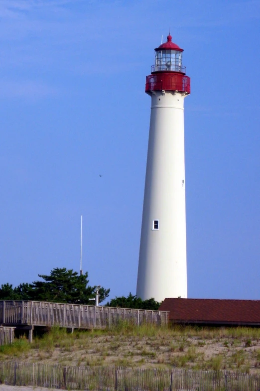 an old lighthouse stands in the distance as people ride on the beach