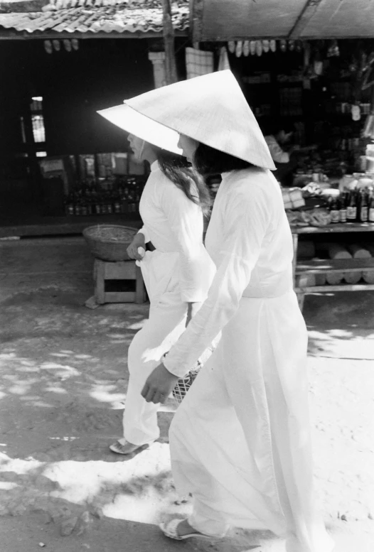 two people wearing hats and dress clothes while walking