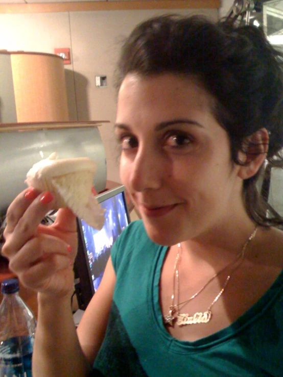 a woman is eating a pastry in front of her computer