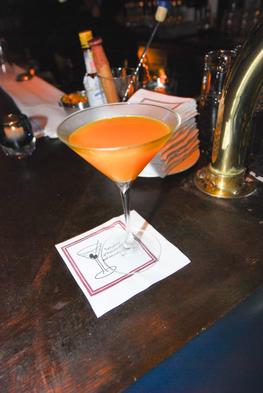 an orange drink in a glass on a bar