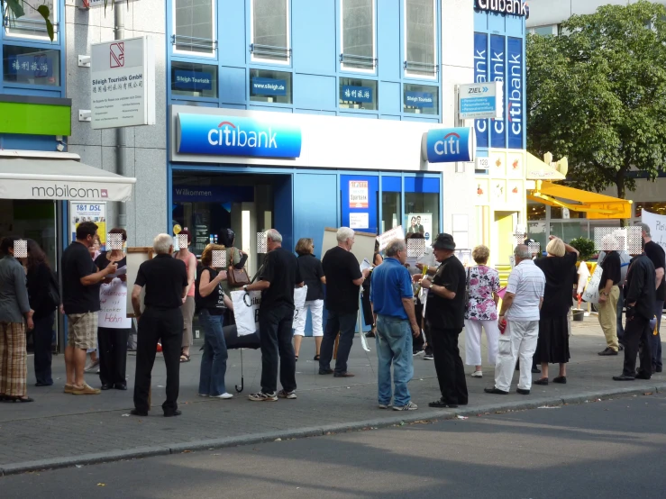 people gather outside on the sidewalk outside a building