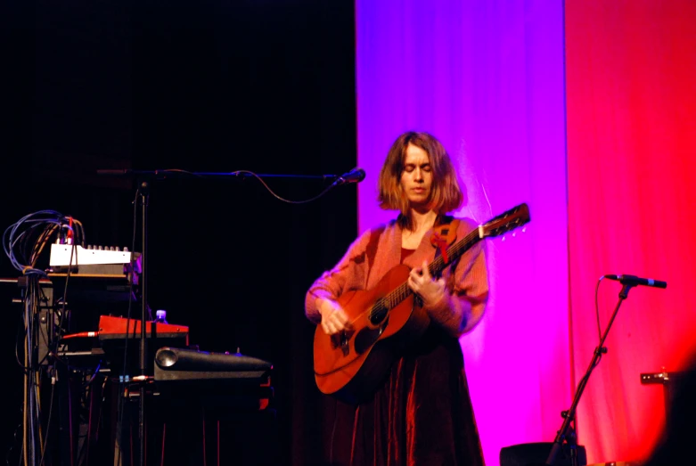 a woman standing on stage playing an acoustic guitar