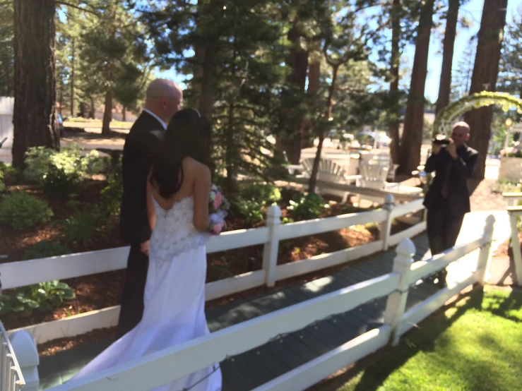 a bride and groom stand on the boardwalk looking at each other