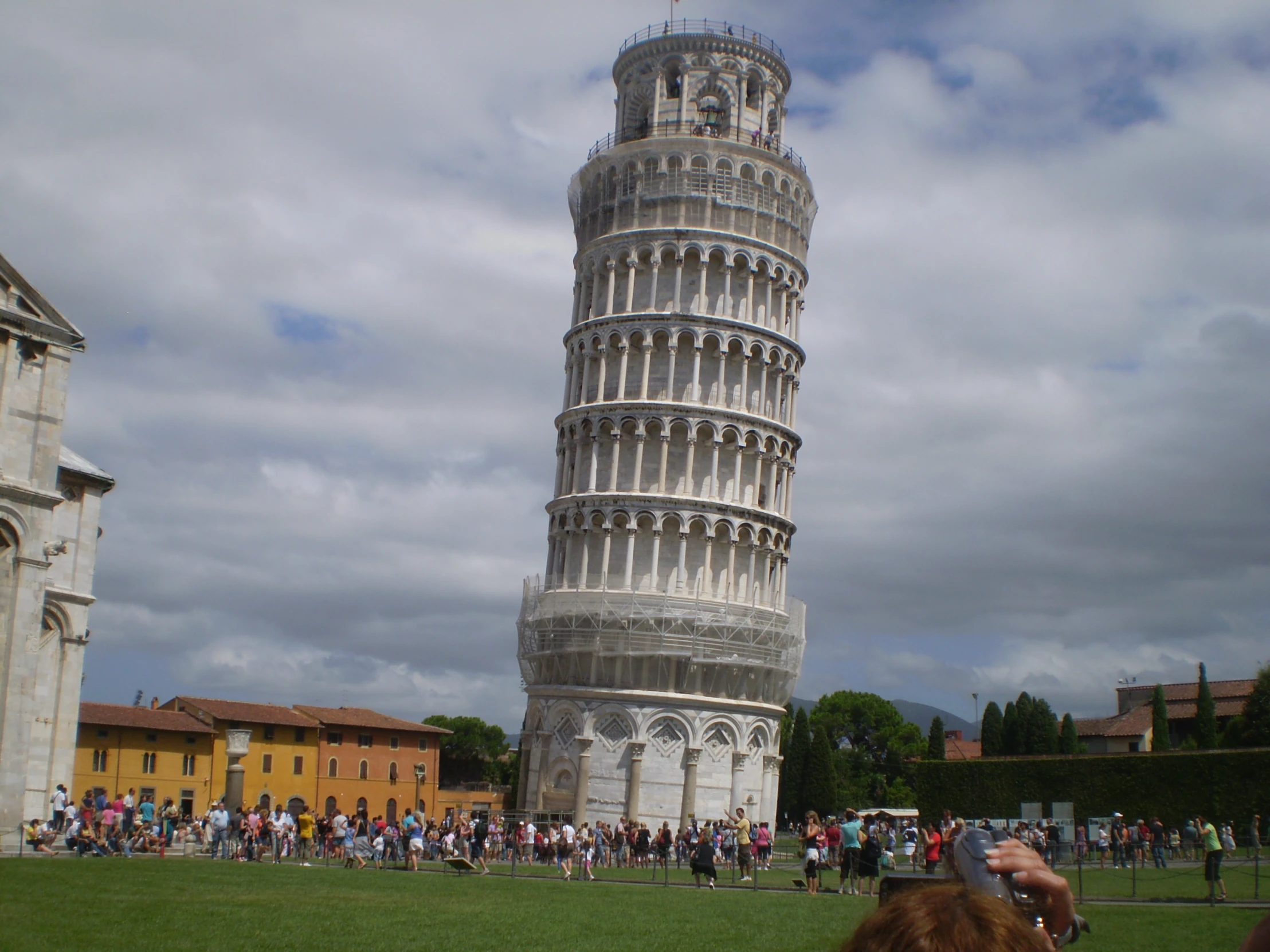 tourists taking pographs next to a leaning tower