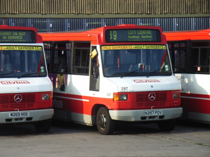 three buses are parked side by side in front of a building
