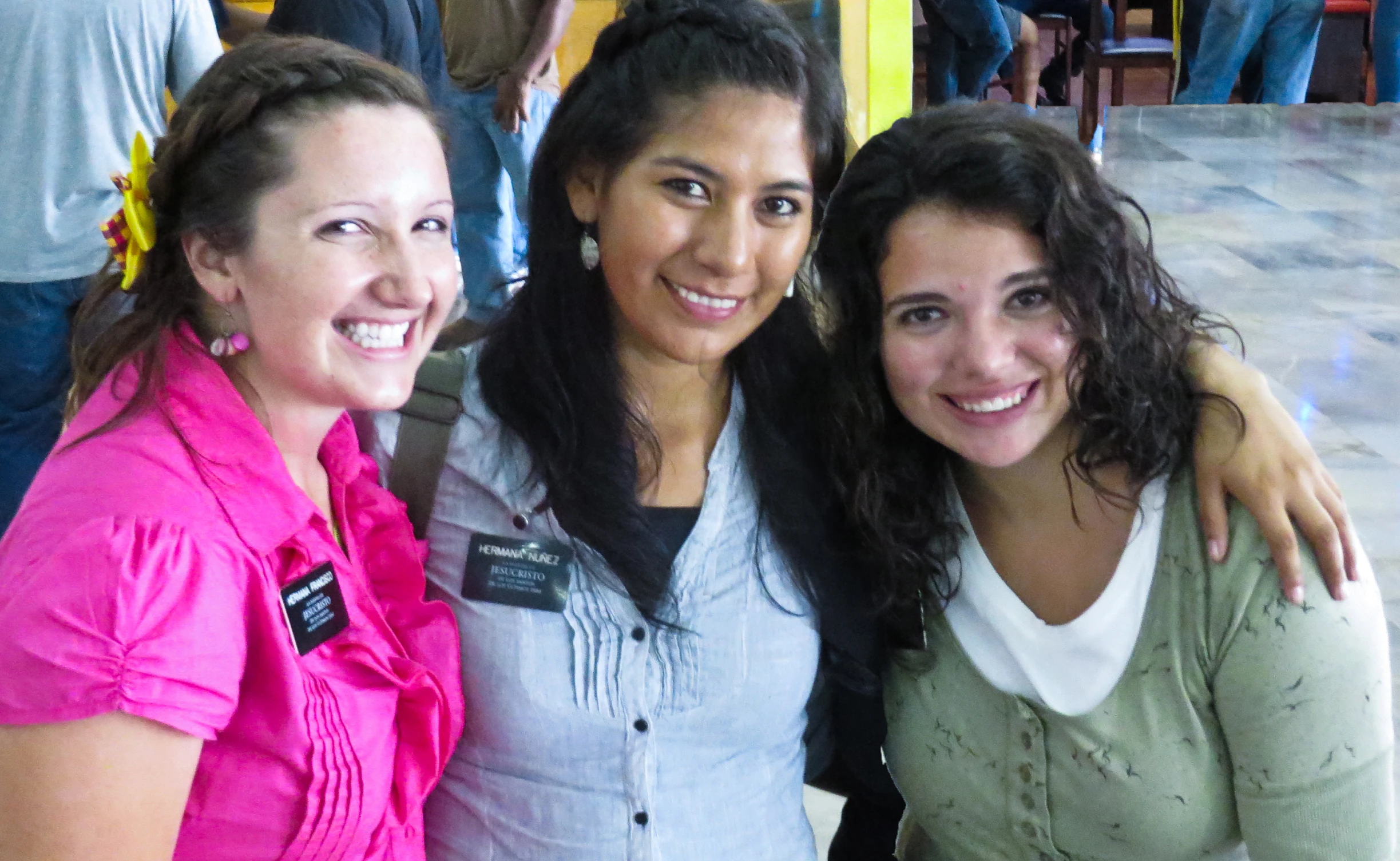 three women smile for the camera while one poses with her arms around another woman