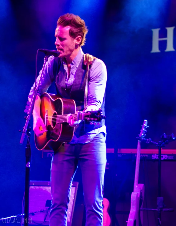 a man holding an acoustic guitar on stage