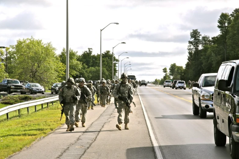 several soldiers walking up a street on the side of a highway