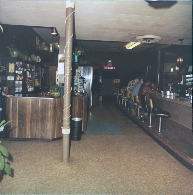 a group of people are sitting at a long bar