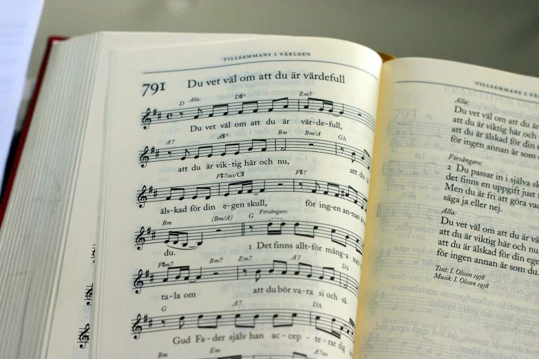 the open book with music notes in cursive language