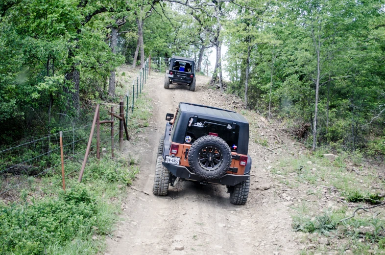 two people in jeeps going up a small dirt hill