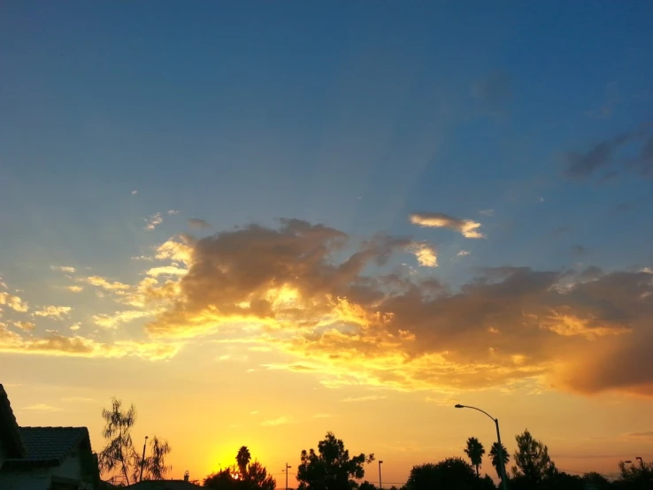 the sun is set over some homes near some trees