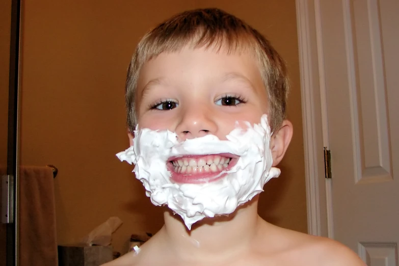 a boy wearing white shaving on his face