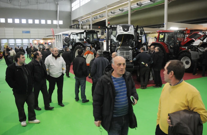 there are many men and some tractors in the shop